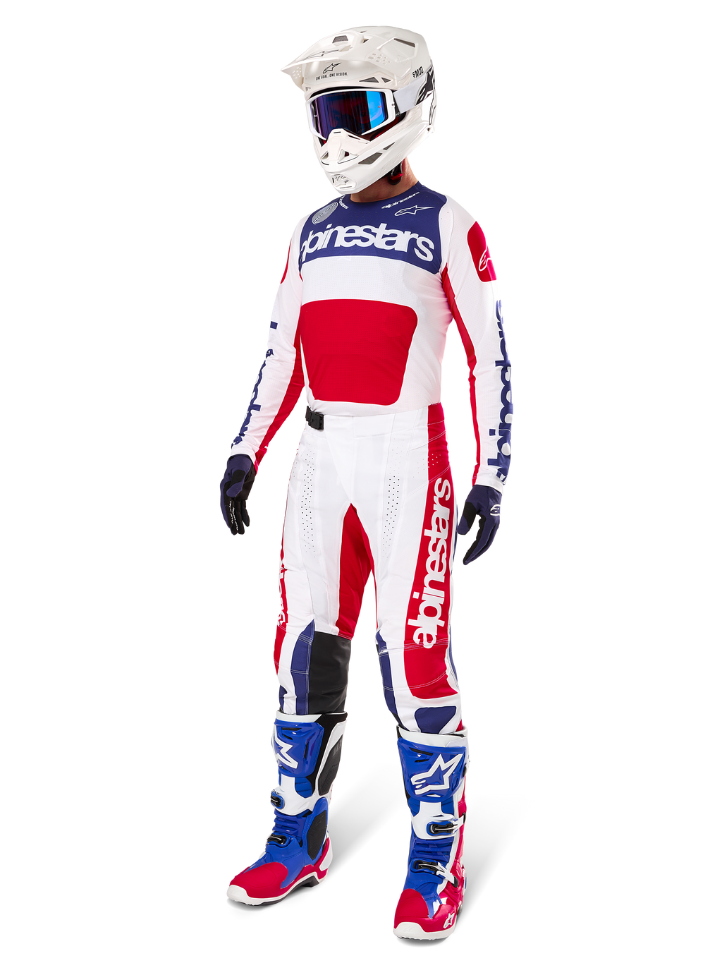 Pilote de motocross portant une tenue de course complète, comprenant le maillot Alpinestars Limited Edition Techstar Fortitude en rouge éclatant, blanc et bleu. Pantalon de motocross assorti, casque blanc avec lunettes bleues et bottes bleues et rouges, offrant un look coordonné pour la compétition tout-terrain.