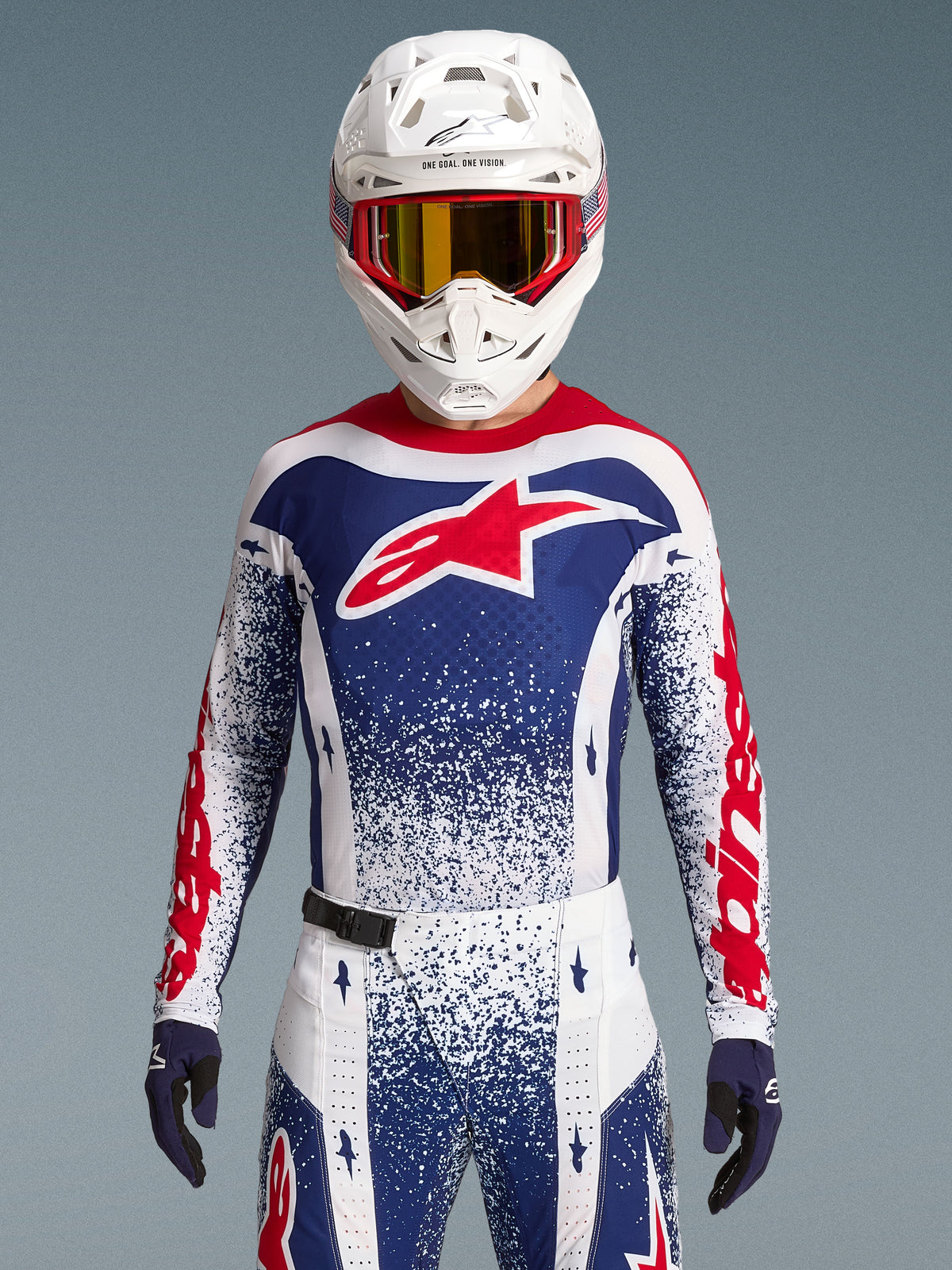 Maillot Alpinestars Techstar Unity, maillot de motocross édition limitée rouge, blanc et bleu, coupe athlétique sur un pilote.