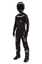 Pilote de motocross Alpinestars portant une tenue de course complète, maillot Supertech Ward 2024 Noir Rouge Berry, maillot noir avec marquage blanc, pantalon noir avec empiècements latéraux rouges et grands logos Astars blancs, casque, gants et bottes noirs, tenue professionnelle coordonnée pour le tout-terrain