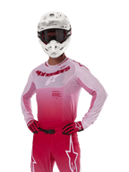 Maillot Alpinestars Supertech Dade 2024, équipement de course de motocross, design en dégradé Red Berry Lilac, maillot à manches longues avec perforations découpées au laser, porté par un pilote avec un casque blanc et des gants et pantalon rouges assortis, tenue de motocross professionnelle sur fond blanc