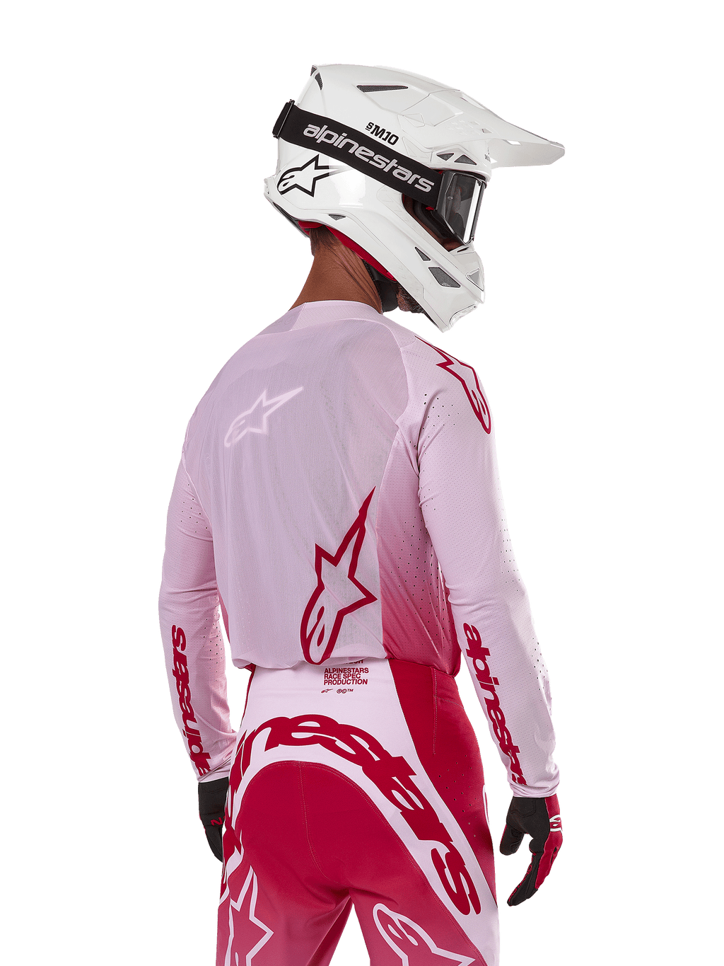 Pilote de motocross vu de dos portant le maillot Alpinestars 2024 Supertech Dade en Red Berry Lilac, avec panneaux en maille respirante et logos Alpinestars rouges, assorti d'un pantalon rouge et lilas et d'un casque Alpinestars blanc avec lunettes, équipement de course tout-terrain professionnel