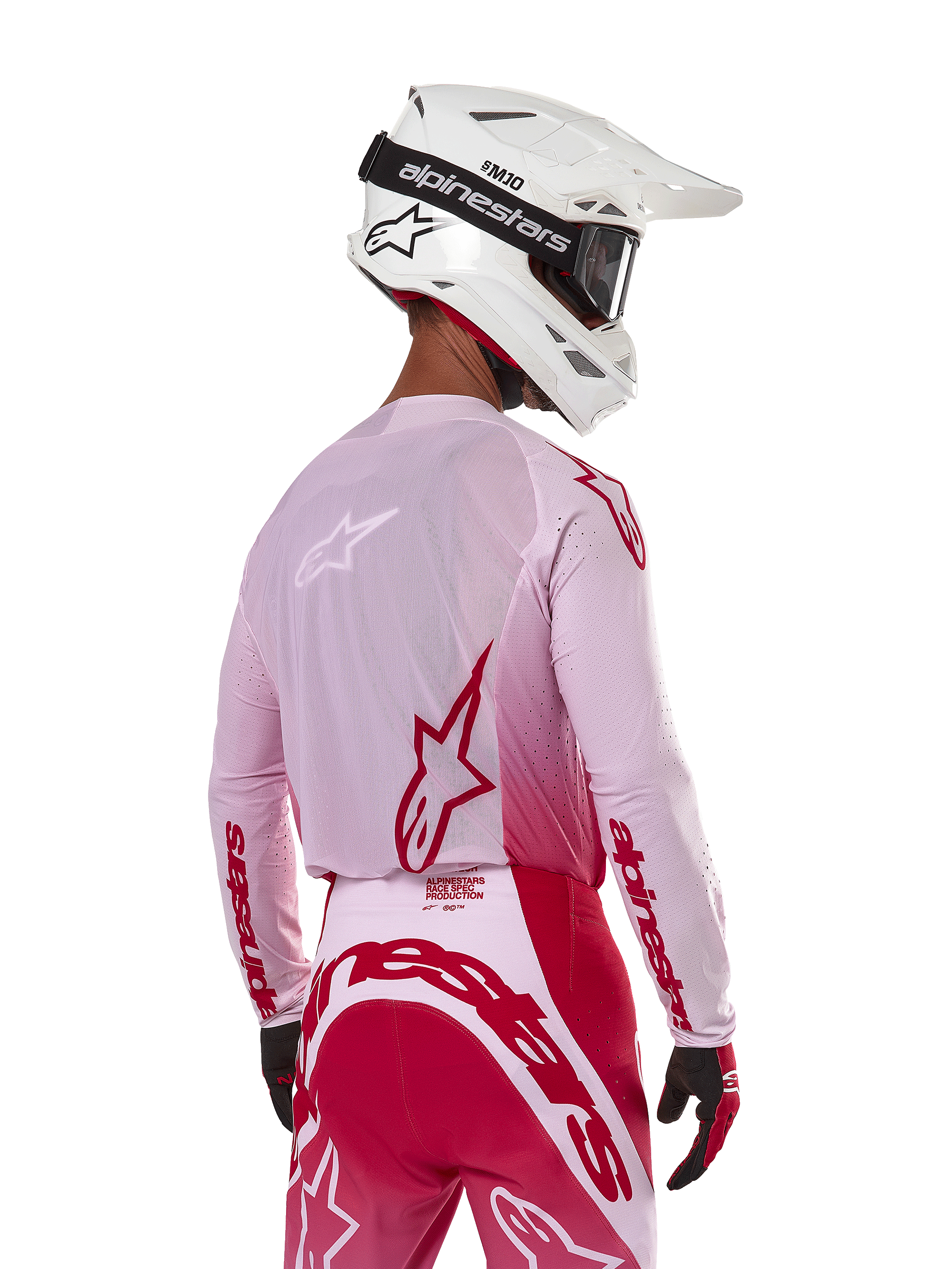 Pilote de motocross vu de dos portant le maillot Alpinestars 2024 Supertech Dade en Red Berry Lilac, avec panneaux en maille respirante et logos Alpinestars rouges, assorti d'un pantalon rouge et lilas et d'un casque Alpinestars blanc avec lunettes, équipement de course tout-terrain professionnel