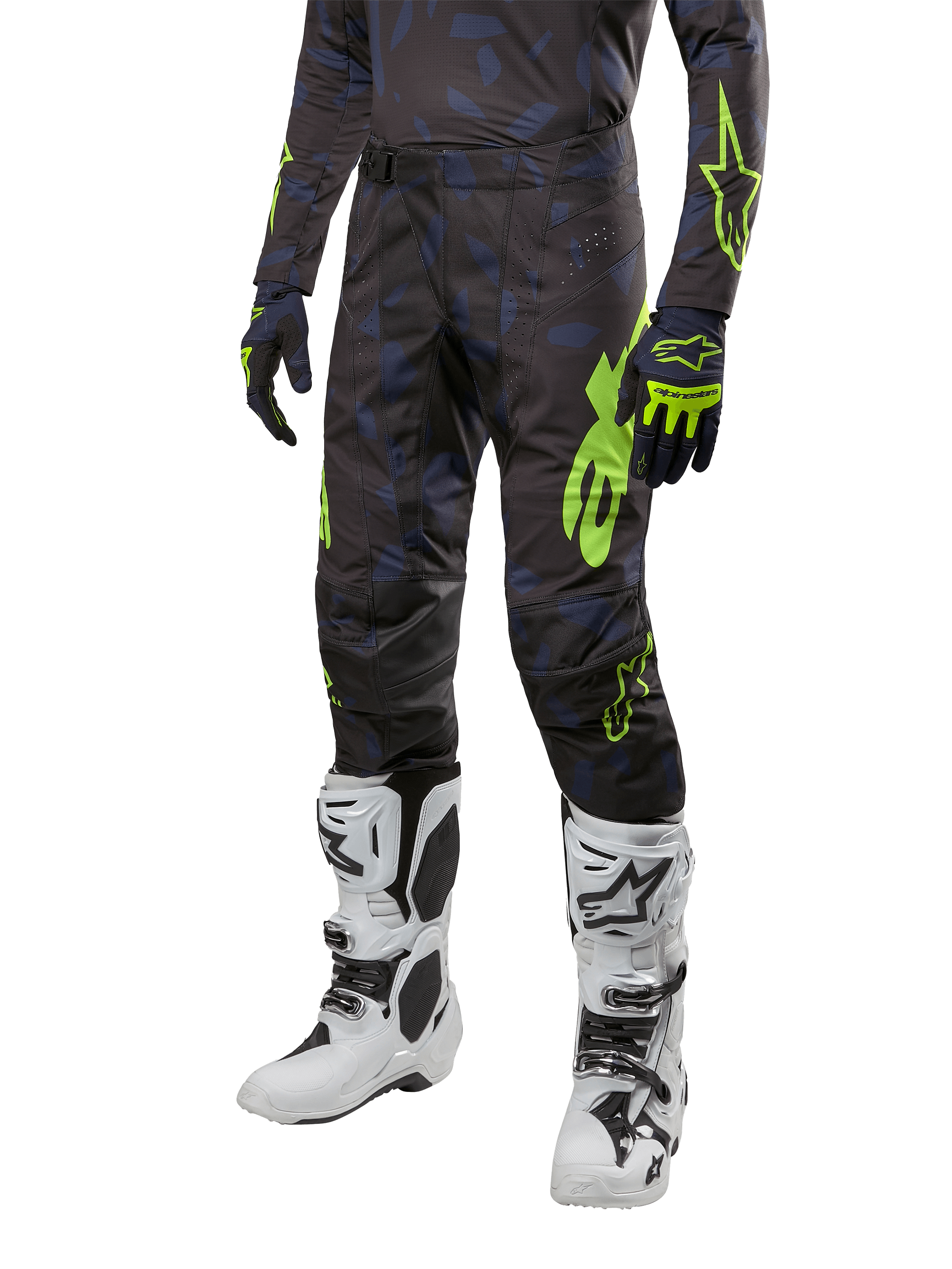 Pantalon Alpinestars Techstar Rantera 2024, pantalon de motocross, noir, bleu marine et jaune fluo, avec motifs camouflage bleu marine et logos vert néon, porté avec des gants assortis et des bottes blanches, coupe racing durable pour la performance tout-terrain