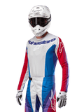 Maillot Alpinestars Techstar Pneuma 2024, maillot de motocross, bleu Mars, rouge et blanc avec des accents violets, coupe athlétique racing, équipement de performance à manches longues porté avec un casque et des gants blancs