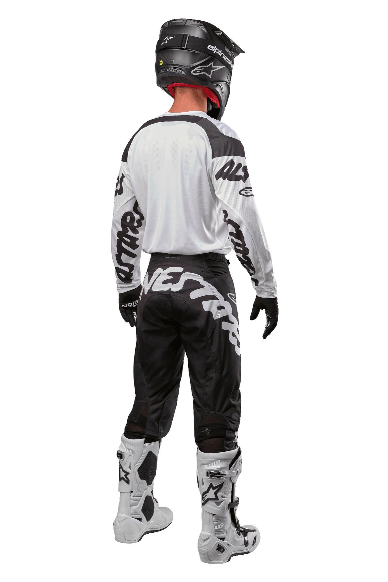 Maillot Alpinestars Racer Hana 2024, vue arrière d'un pilote de motocross, blanc et noir, maillot blanc avec marquage graphique noir sur les manches, associé à un pantalon noir avec lettrage Alpinestars blanc sur l'assise, casque noir et bottes blanches et noires, équipement de course tout-terrain coordonné