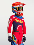 Maillot Supertech Dyna Junior Alpinestars, rouge et bleu marine, équipement de motocross en maille légère porté par un enfant.