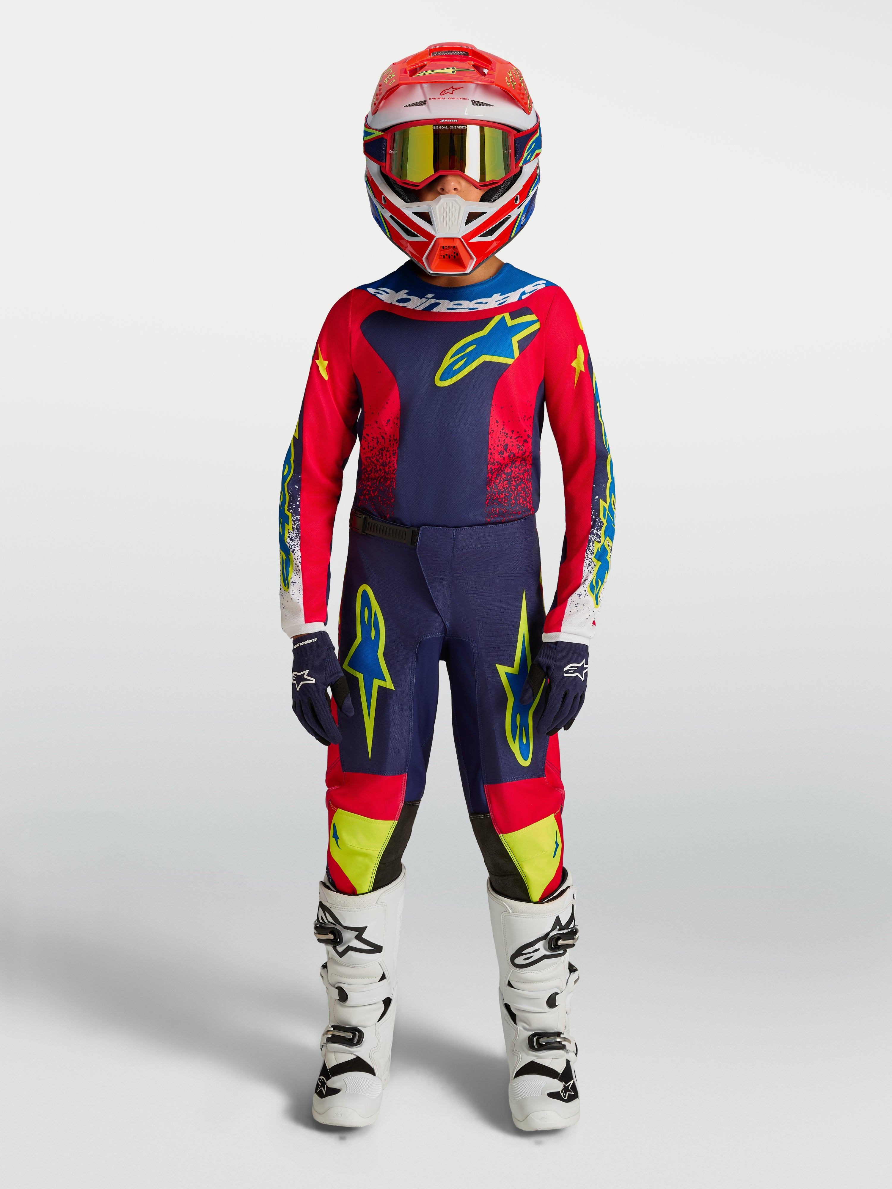 Ensemble Alpinestars Fluid Drag Junior 2027, tenue de motocross bleu marine et rouge feu avec bottes blanches.