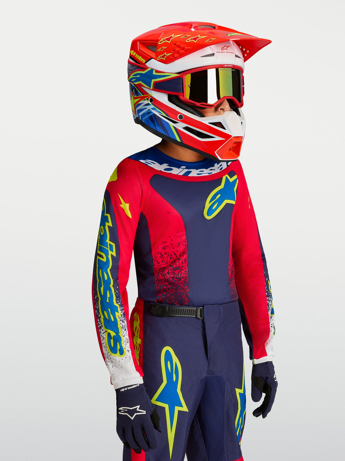 Alpinestars maillot Fluid Drag junior, équipement de motocross, bleu marine et rouge, avec un casque de course assorti.