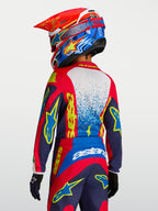 Maillot Fluid Drag Junior 2027 d'Alpinestars, maillot de motocross pour enfant, rouge et bleu marine avec graphismes jaunes, vue de dos sur un jeune pilote