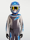 Alpinestars Maillot Fluid Drag Junior 2027, maillot de motocross gris et bleu pour enfant, conçu en poly-tissu respirant et évacuant l'humidité, porté avec un équipement MX complet.