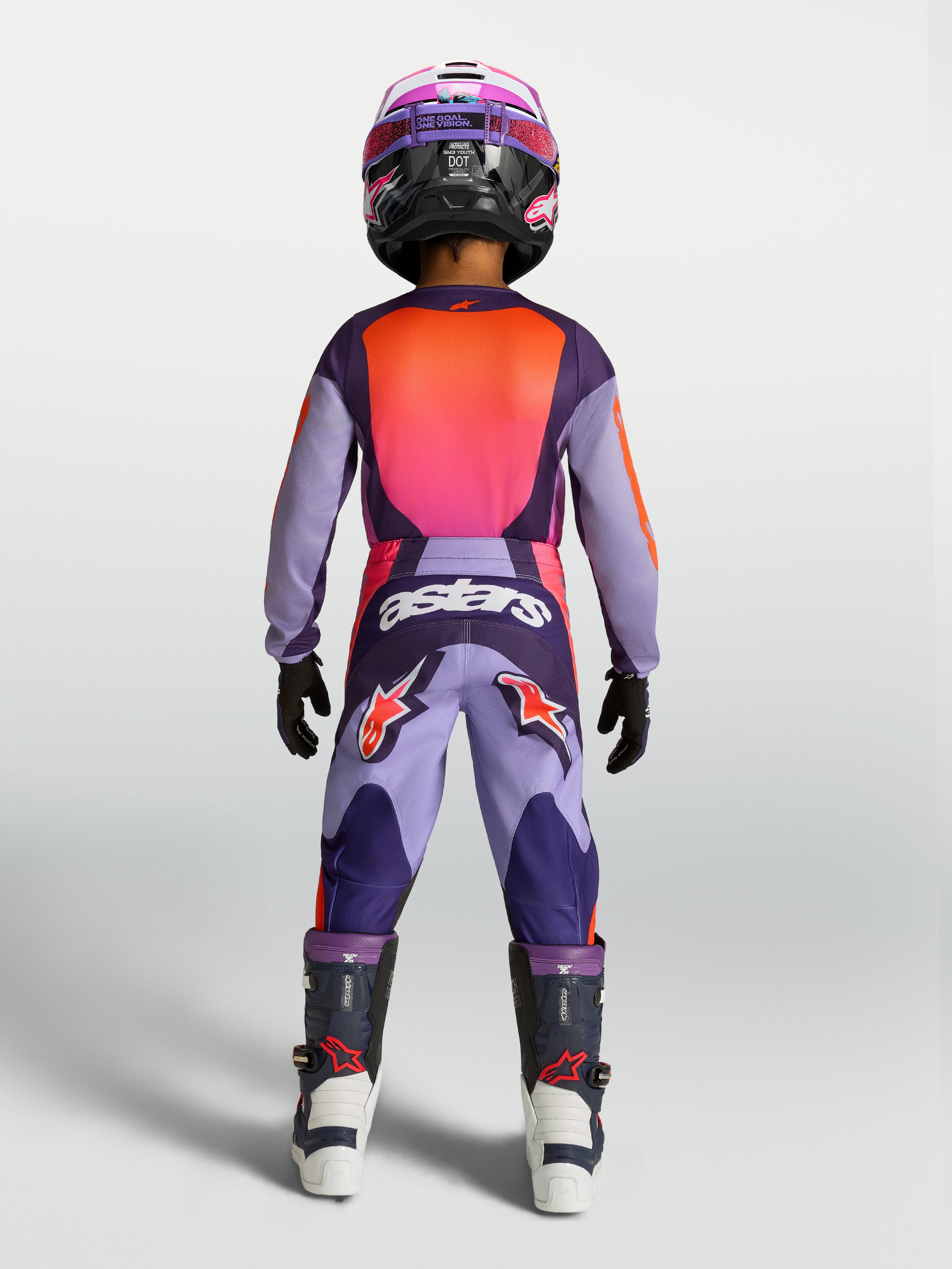 Alpinestars maillot Fluid Hunt Junior 2027 et ensemble MX, violet et rose fluo, vue de dos sur un jeune pilote
