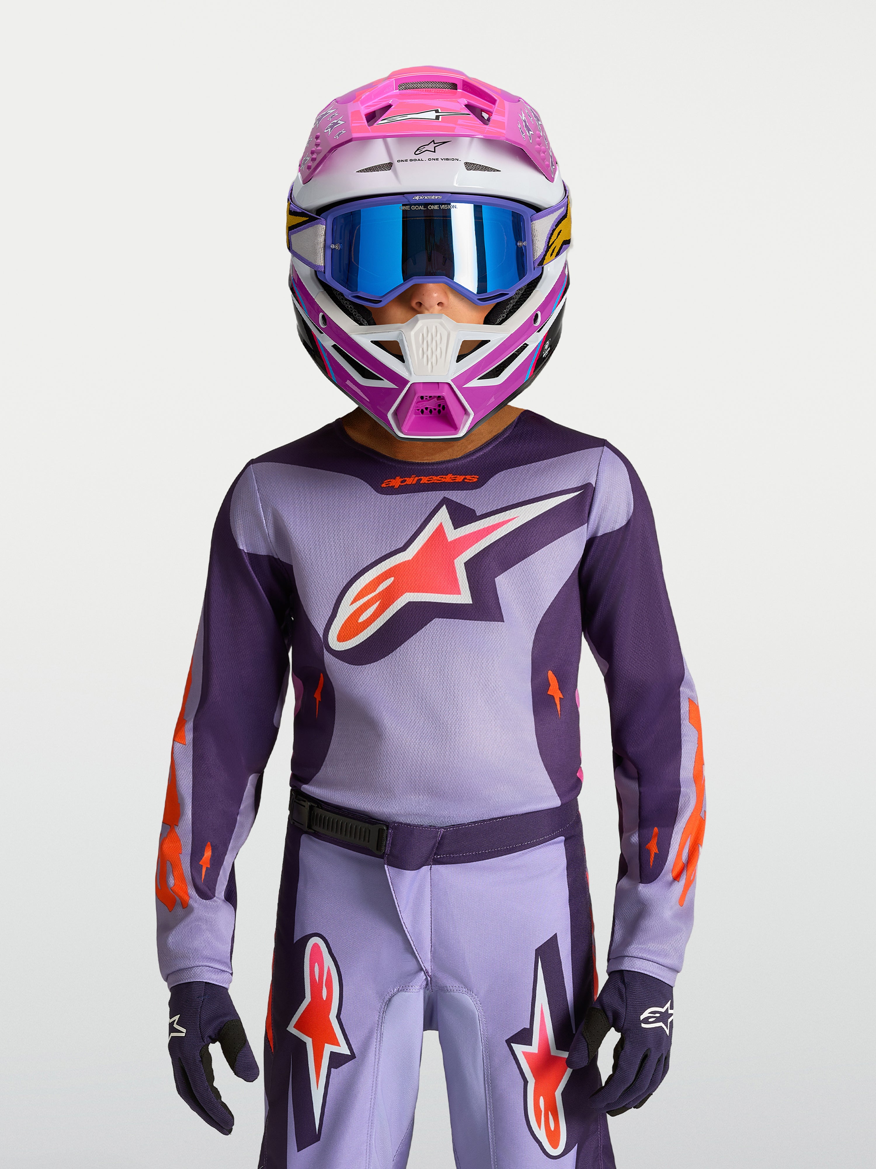 Maillot Fluid Hunt Junior 2027 d'Alpinestars, tenue de motocross violette et rose fluo avec casque et masque.