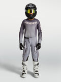 Alpinestars maillot et ensemble Fluid Amber junior 2027, tenue de motocross grise et sable, casque noir et bottes blanches.