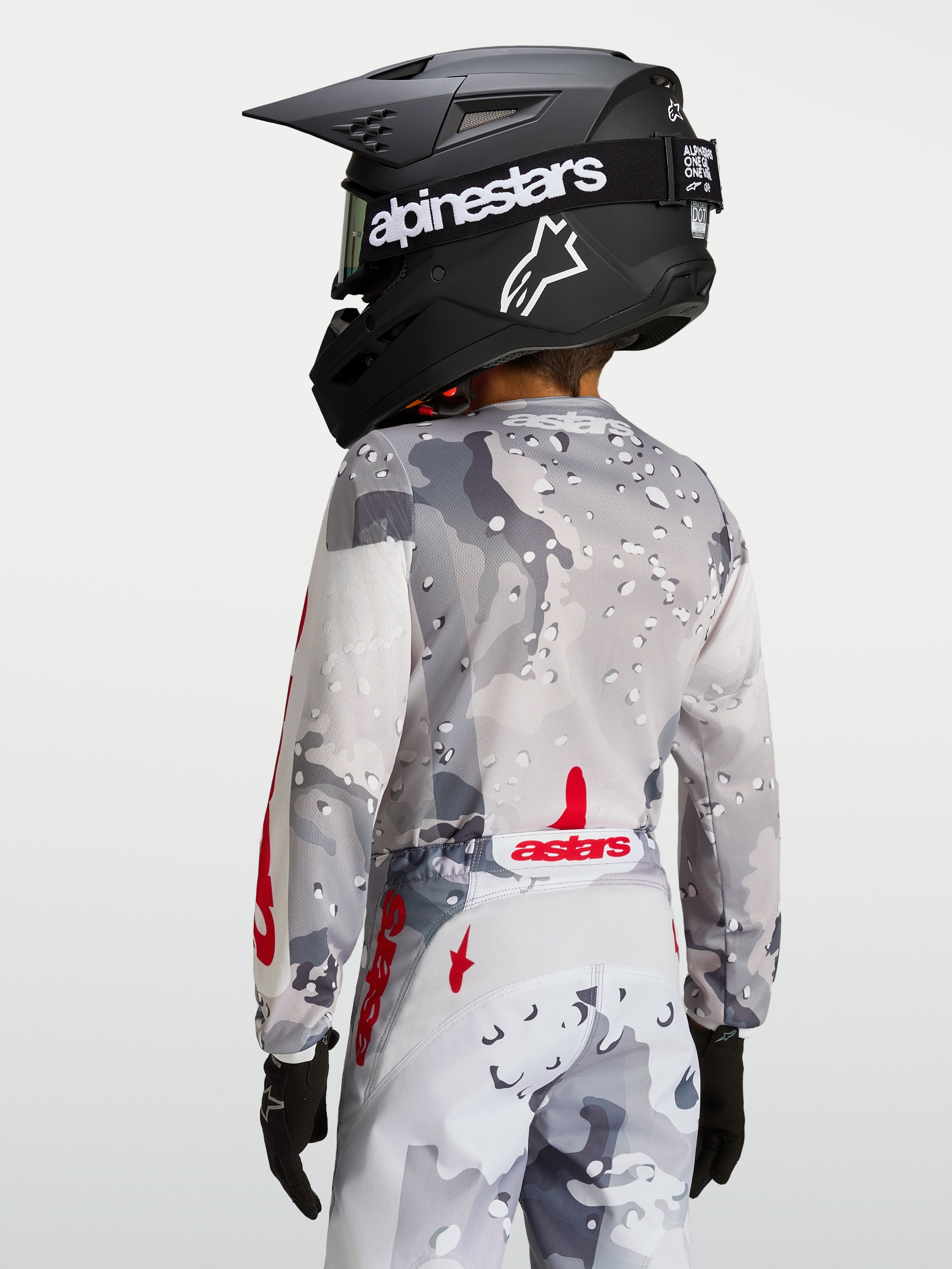 Alpinestars Maillot Fluid Lone Junior, haut de motocross pour enfant, gris camouflage et rouge, vue arrière montrant la coupe ergonomique et le bas du dos rallongé pour la conduite tout-terrain.