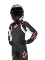 Maillot Racer Lucent Junior 2024, maillot de motocross, noir, blanc et rouge, porté par un jeune pilote avec un casque noir et un pantalon assorti, arborant des logos d'étoiles rouges et des accents graphiques blancs, équipement de performance tout-terrain pour la course de motocross