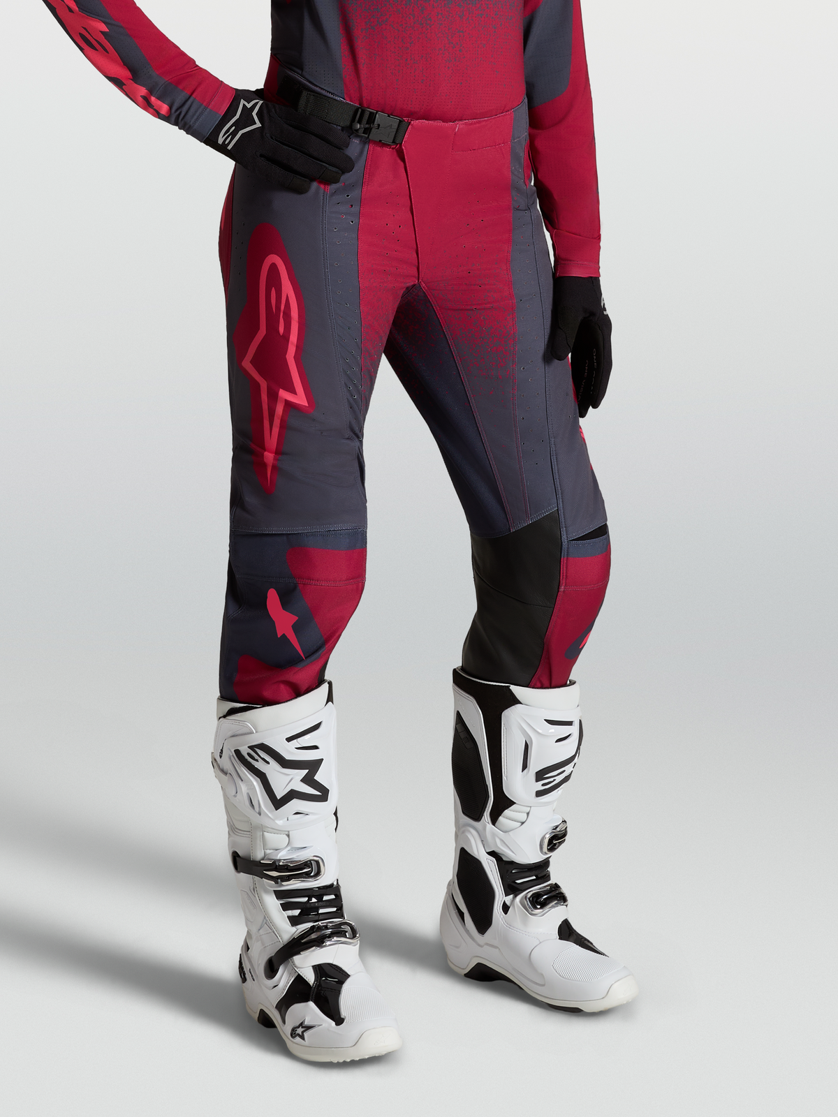 Alpinestars Stella Techstar Swan, pantalon de motocross pour femme, rouge et gris, porté avec bottes Tech 10 blanches.
