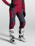 Alpinestars Stella Techstar Swan, pantalon de motocross pour femme, rouge et gris, porté avec bottes Tech 10 blanches.
