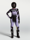 Alpinestars Stella Techstar Swan Gear Set, ensemble de motocross pour femme, violet et noir, maillot et pantalon portés par une pilote avec casque et bottes.