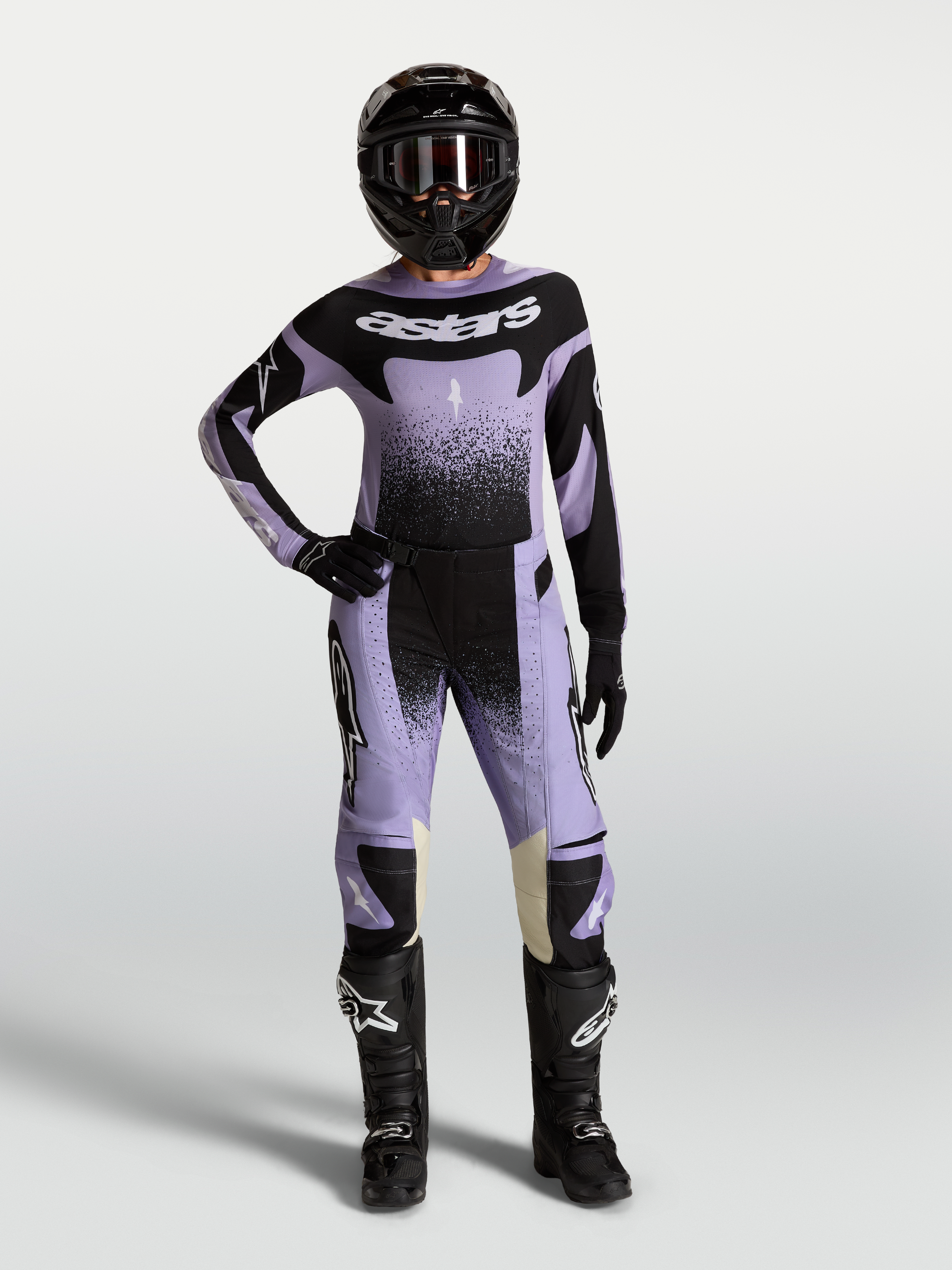 Alpinestars Stella Techstar Swan Gear Set, ensemble de motocross pour femme, violet et noir, maillot et pantalon portés par une pilote avec casque et bottes.