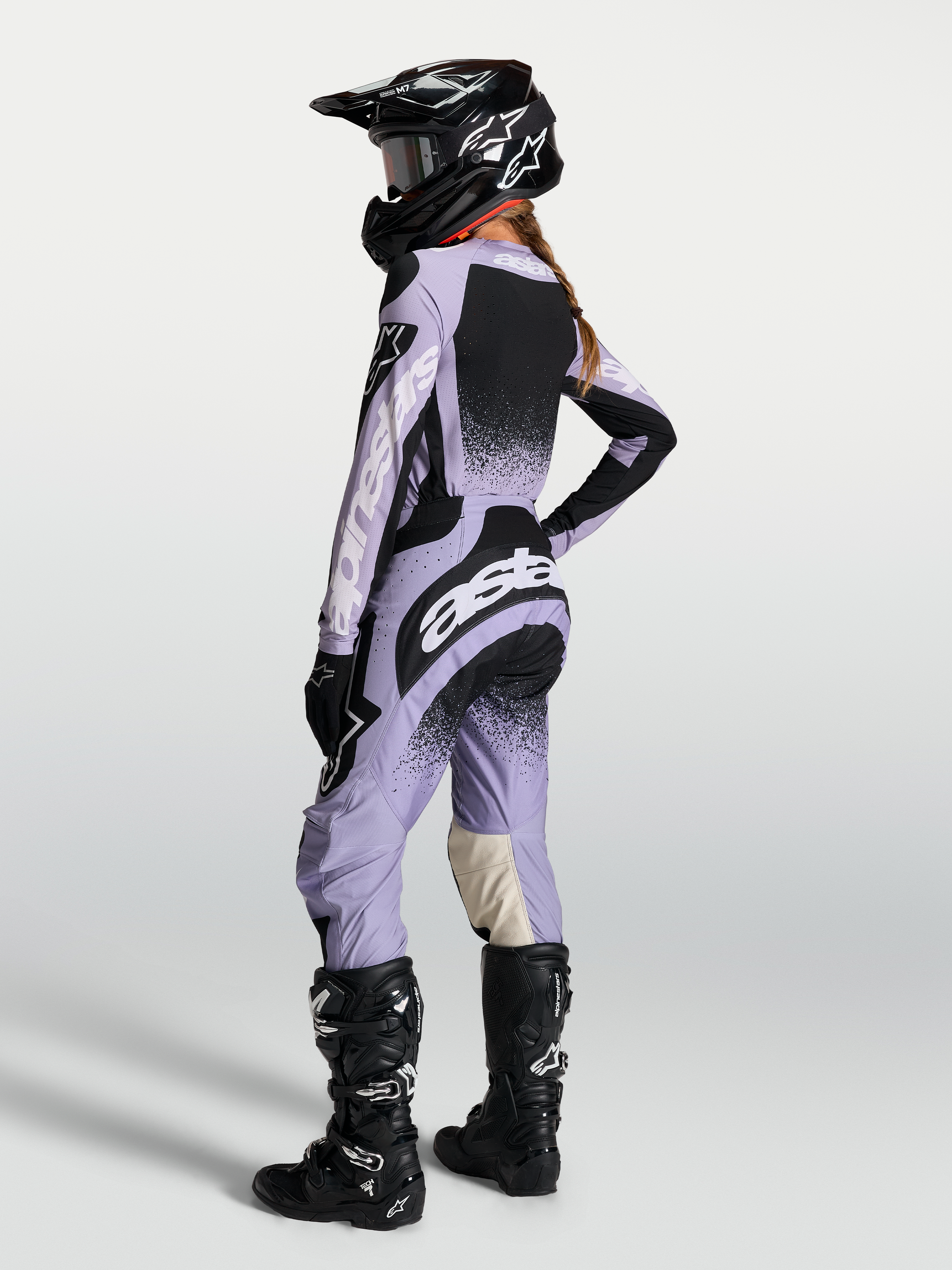 Maillot Stella Techstar Swan et ensemble Alpinestars pour femme, violet clair et noir, vue de dos avec casque et bottes.