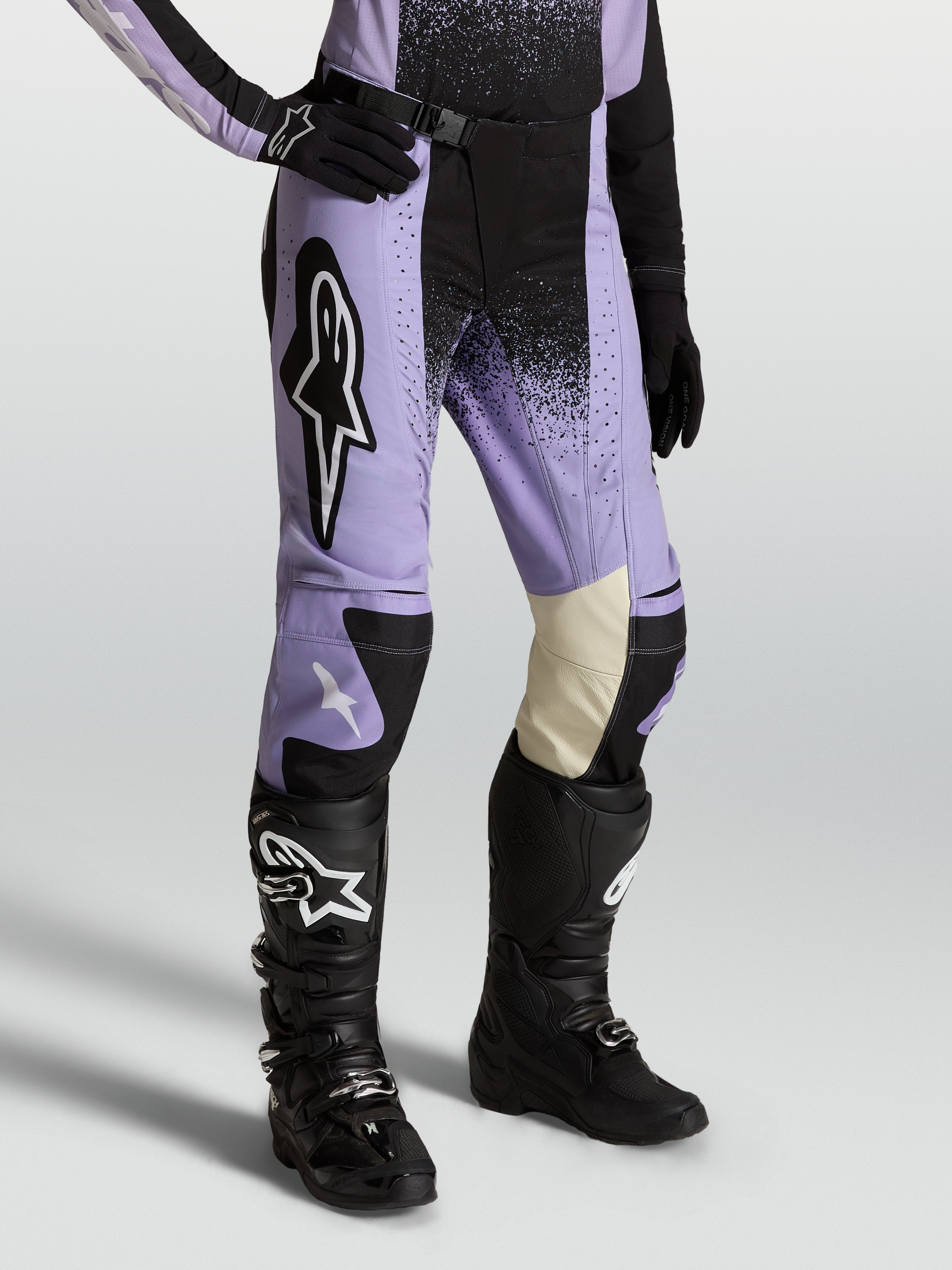 Alpinestars Stella Techstar Swan, pantalon de motocross pour femme, coloris violet et noir, porté avec des bottes et gants noirs, construction en poly-tissu durable et cuir aux genoux pour une performance tout-terrain optimale
