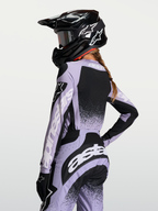 Maillot Stella Techstar Swan Alpinestars, haut de motocross pour femme, violet et noir, tissu respirant et coupe de course, vue de dos avec casque et logos blancs