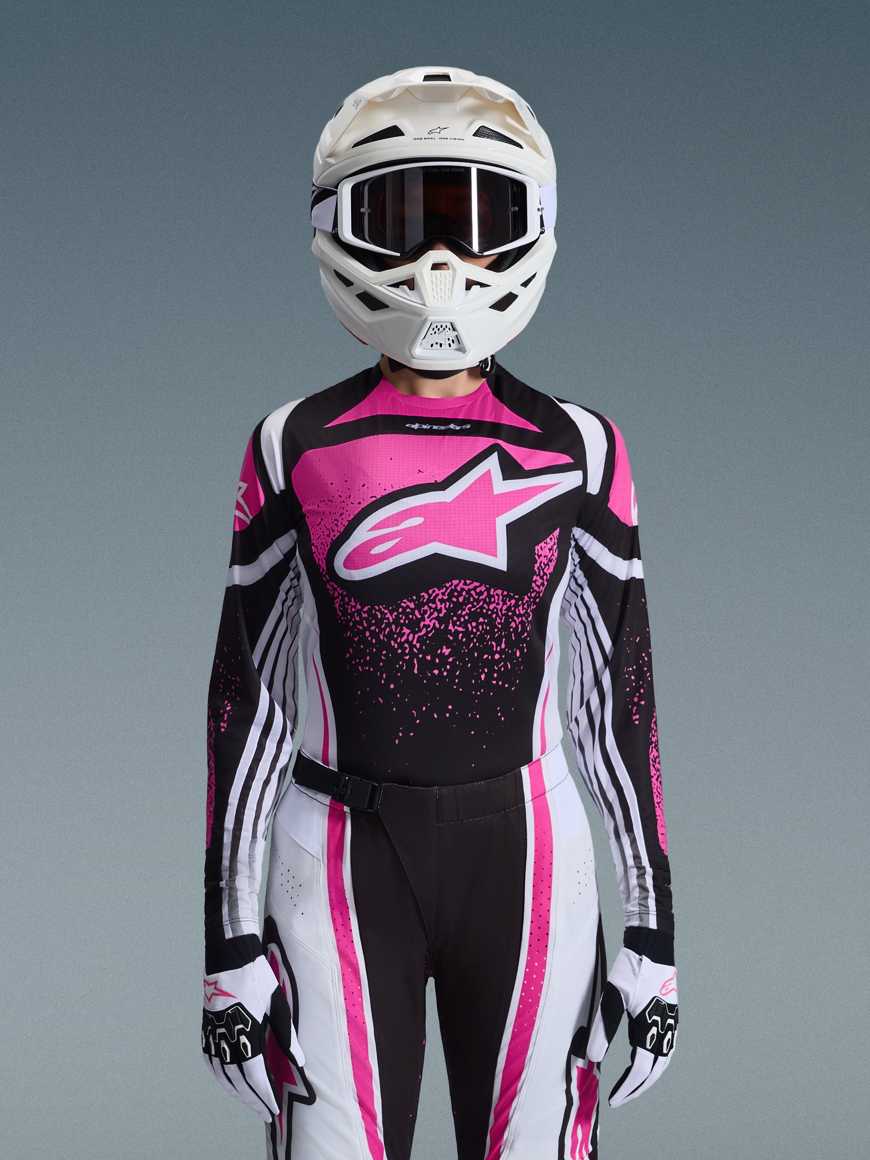 Ensemble d'équipement Alpinestars Stella Techstar Nomur 2026, tenue de motocross pour femme, rose, noir et blanc avec un grand logo étoile, comprenant un maillot, un pantalon et des gants assortis avec un casque blanc, vue de face sur fond gris