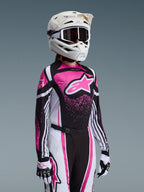 Pilote de motocross féminine portant l'ensemble d'équipement Alpinestars Stella Techstar Nomur 2026 en rose, noir et blanc ; comprend un maillot avec un grand logo d'étoile rose, un pantalon assorti avec boucle de fermeture magnétique, un casque blanc avec lunettes et des gants blancs et noirs.