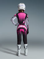 Ensemble d'équipement Alpinestars 2026 Stella Techstar Nomur, pilote de motocross vue de dos, maillot rose et noir avec manches à rayures blanches et motif moucheté, pantalon assorti avec logo Alpinestars blanc, casque blanc et bottes tout-terrain blanches