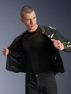 Mannequin homme portant la veste Alpinestars T-Sps Air V2 en noir et jaune fluo, présentée ouverte pour mettre en évidence la construction interne en mesh et les poches, associée à une couche de base Alpinestars noire et un pantalon noir, style d'équipement de moto urbain