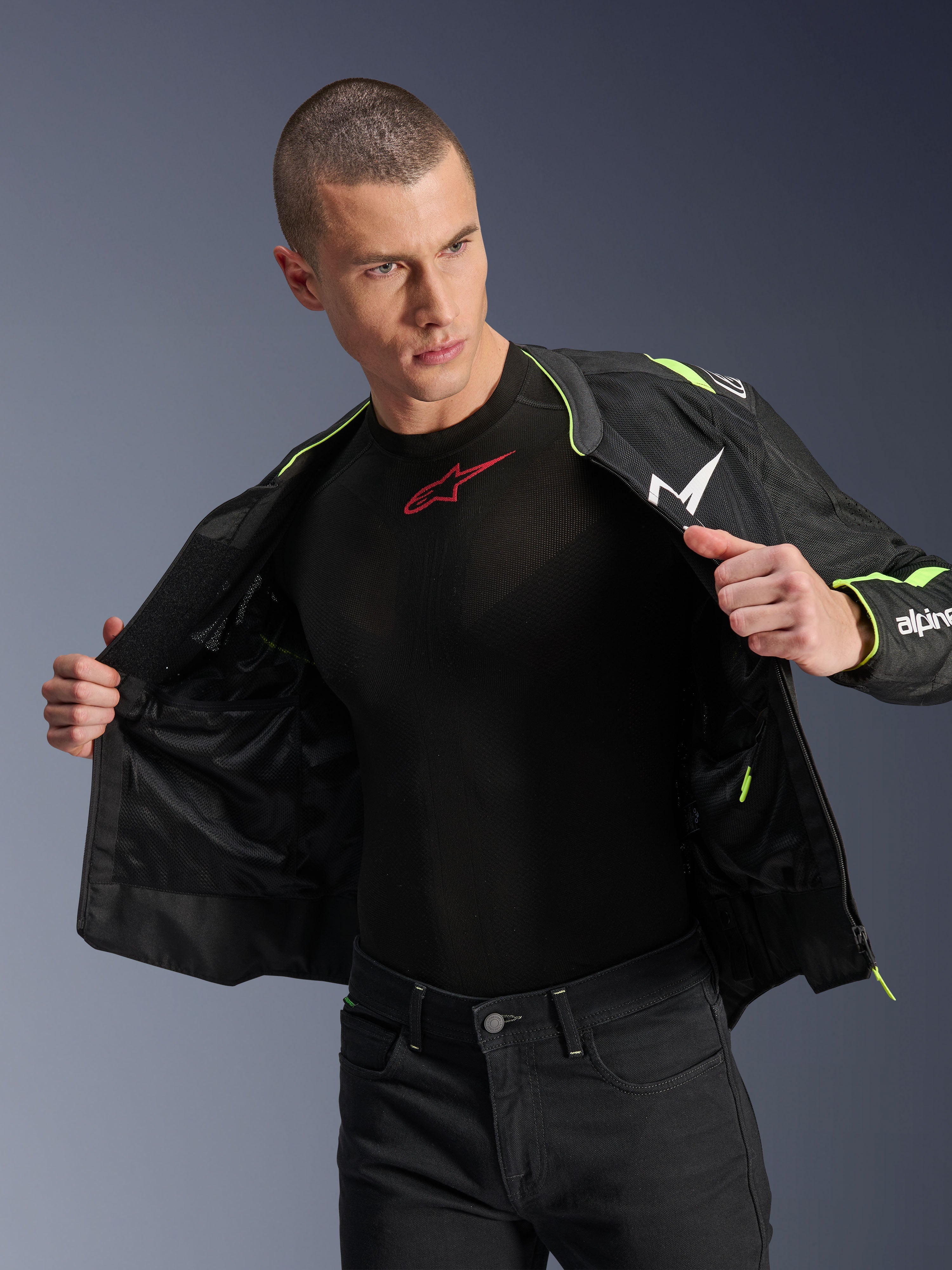 Mannequin homme portant la veste Alpinestars T-Sps Air V2 en noir et jaune fluo, présentée ouverte pour mettre en évidence la construction interne en mesh et les poches, associée à une couche de base Alpinestars noire et un pantalon noir, style d'équipement de moto urbain
