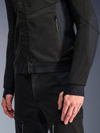 Veste Alpinestars Troop-Air Pro en Noir Noir, gros plan d'une veste d'air technique blindée présentant une structure en maille 2D détaillée, des poches zippées et un ourlet élastiqué avec logo Alpinestars, manches avec passants de pouce intégrés, associée à un équipement de moto assorti.