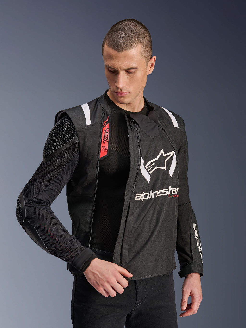 Veste Alpinestars T-Stunt Air, veste de moto noire et blanche portée par un mannequin homme, mettant en évidence la construction modulaire en mesh et les protections internes apparentes aux épaules et aux coudes, logo Alpinestars sur la poitrine, compatible Tech-Air®, coupe sportive pour la route