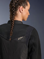 Veste Alpinestars Stella T-Dyno Air, veste de moto noire pour femme, vue arrière rapprochée montrant des panneaux en maille 3D sur l'empiècement et le haut du dos pour la circulation de l'air, avec un petit logo étoile blanc, portée par un mannequin aux cheveux tressés