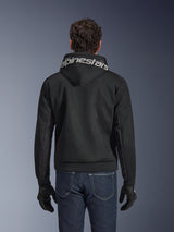 Alpinestars Chrome Superairflow Hoodie, Black motorcycle hoodie, rear view featuring bold white Alpinestars branding across the hood, 3D technical mesh construction, worn with dark blue jeans and black gloves, ventilated urban riding apparel