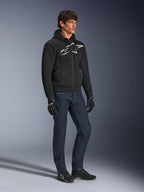 Alpinestars Chrome Superairflow Hoodie, black with white and gray logo, 3D mesh ventilated textile construction, worn with dark blue denim jeans and black motorcycle gloves, urban sport riding style.