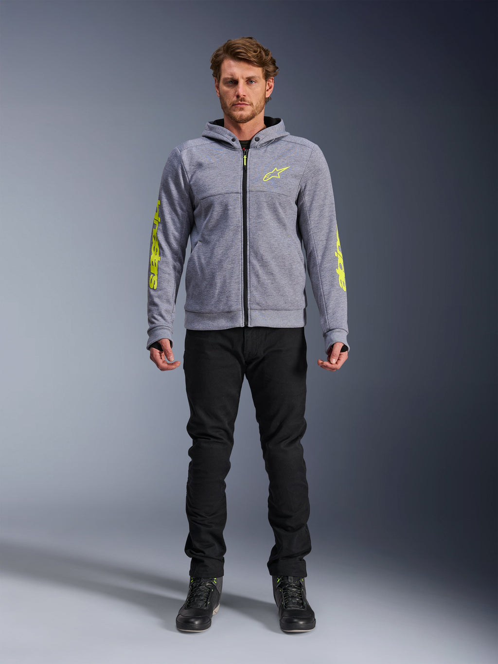 Alpinestars Chrome V2 Sport Hoodie, Gray Heather with Fluorescent Yellow accents, urban motorcycle apparel, featured with black pants and black riding shoes, technical fleece with bold yellow branding on sleeves and chest, casual street style for riding