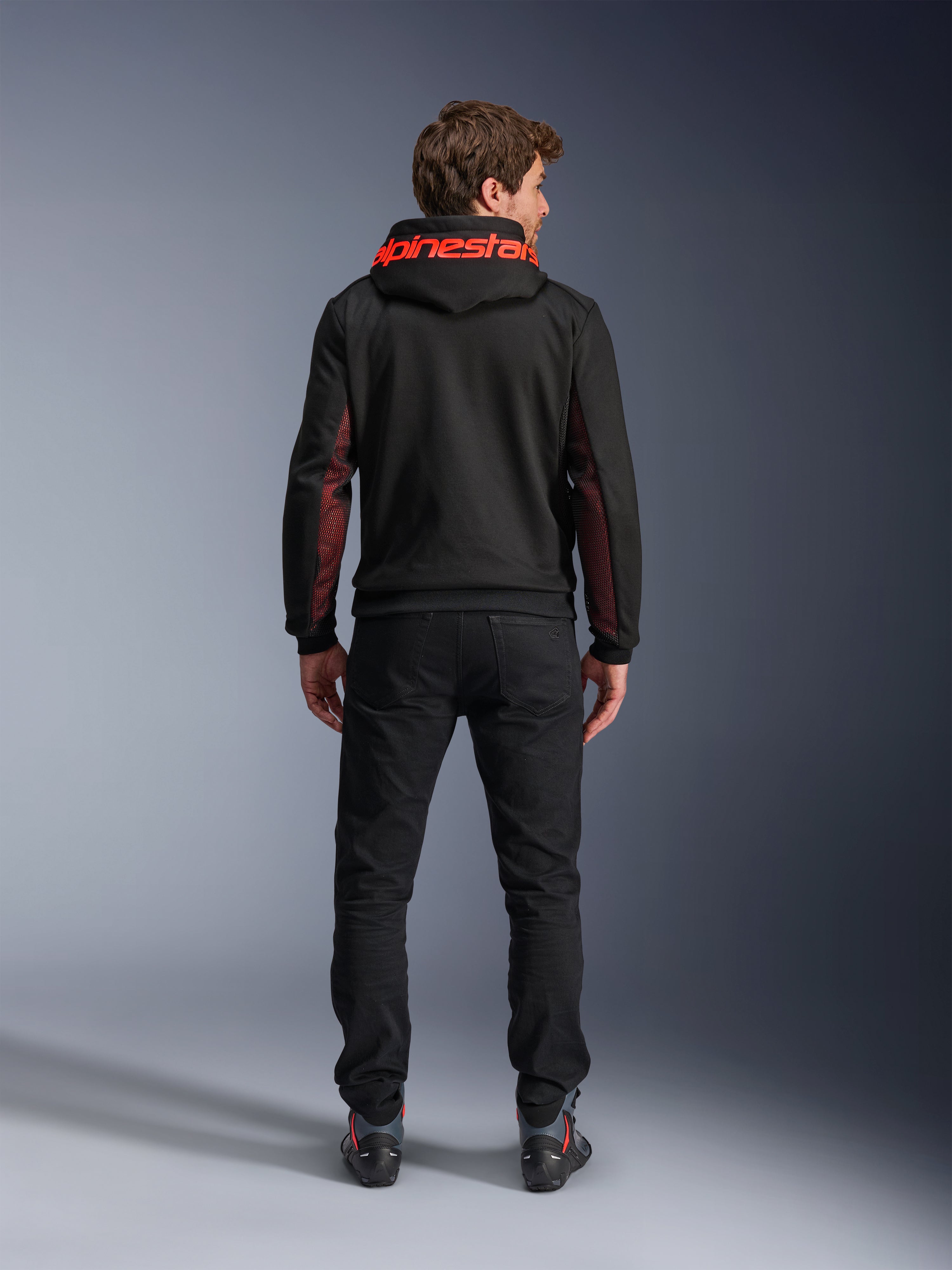 Alpinestars Chrome Air Sport Hoodie, Black and Red Fluo, back view of man wearing casual motorcycle jacket, featuring red Alpinestars branding on the hood and red mesh panels on the sleeves, paired with black pants.