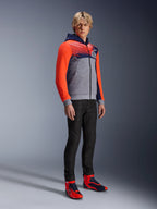 Alpinestars MM93 Chrome V2 Sport Hoodie, urban motorcycle hoodie, gray melange body with navy blue chest and bright red fluo sleeves, featuring the 93 logo on the chest, worn by a model with slim-fit black pants and coordinated red and blue high-top riding shoes, modern athletic fit for street riding