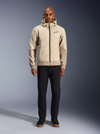 Sweat à capuche Alpinestars Radium Tech en Mastic Aluminum, hoodie de moto urbain porté par un mannequin homme avec un pantalon noir et des bottes noires, doté d'une fermeture éclair noire intégrale, d'un petit logo sur la poitrine et d'une coupe athlétique pour la conduite urbaine.