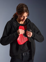Alpinestars Stella Chrome Superairflow Hoodie, hoodie de moto pour femme, noir, mannequin tenant une protection de poitrine Nucleon rouge, construction en maille 3D légère pour la conduite urbaine et sportive