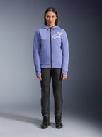 Sweat à capuche Alpinestars Stella Chrome V2 Sport pour femme, bleu violet avec logo Astars blanc sur la poitrine, polaire technique zippée avec capuche, porté avec un pantalon de moto noir et des bottes, équipement de conduite urbaine décontracté pour femme