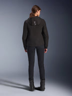 Alpinestars Stella Radium Tech Hoodie pour femme, noir, vue arrière d'un mannequin portant un sweat à capuche technique coupe-vent léger à 3 couches avec logo Alpinestars sur la capuche, associé à un pantalon et des bottes noirs, vêtement de moto urbain