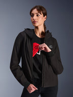 Alpinestars Stella Radium Tech Hoodie pour femme, sweat à capuche de moto urbain noir, mannequin démontrant la protection Nucleon Flex Plus rouge à l'intérieur, coque technique légère à 3 couches coupe-vent avec poignets côtelés et écusson logo, vêtement de protection moto