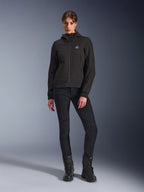 Alpinestars Stella Radium Tech Hoodie en noir, veste technique de moto urbaine pour femme, portée avec un pantalon slim noir et des bottes noires, dotée d'un petit logo sur la poitrine et d'une capuche, construction coupe-vent légère pour la conduite urbaine