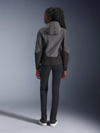 Alpinestars Stella Radium Tech Hoodie pour femme, gris foncé et noir, vue arrière montrant le marquage 'ALPIN' sur la capuche, avec un pantalon noir ajusté et des baskets noires, vêtement de moto urbain