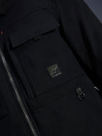 Surchemise Alpinestars Bryon Water Resistant, noir, vue rapprochée du tissu en toile cirée, fermeture éclair avant, poche cargo sur la poitrine avec écusson du logo Alpinestars et détail d'anneau en D en métal