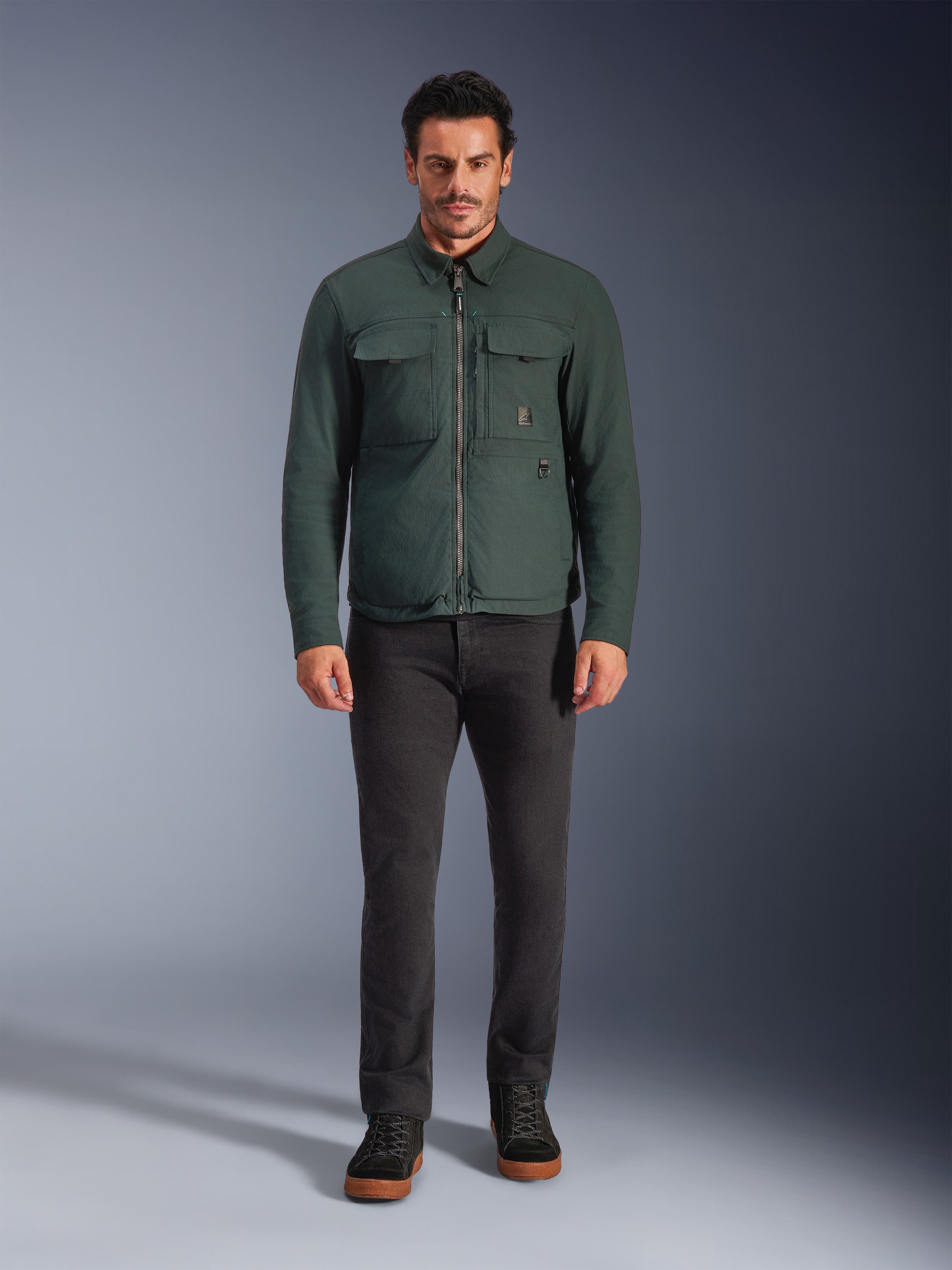 Alpinestars Bryon WR Overshirt, Water-Resistant Motorcycle Jacket, Dark Emerald, worn with black pants and black boots, featuring waxed canvas construction, chest cargo pockets, and a modern urban design.