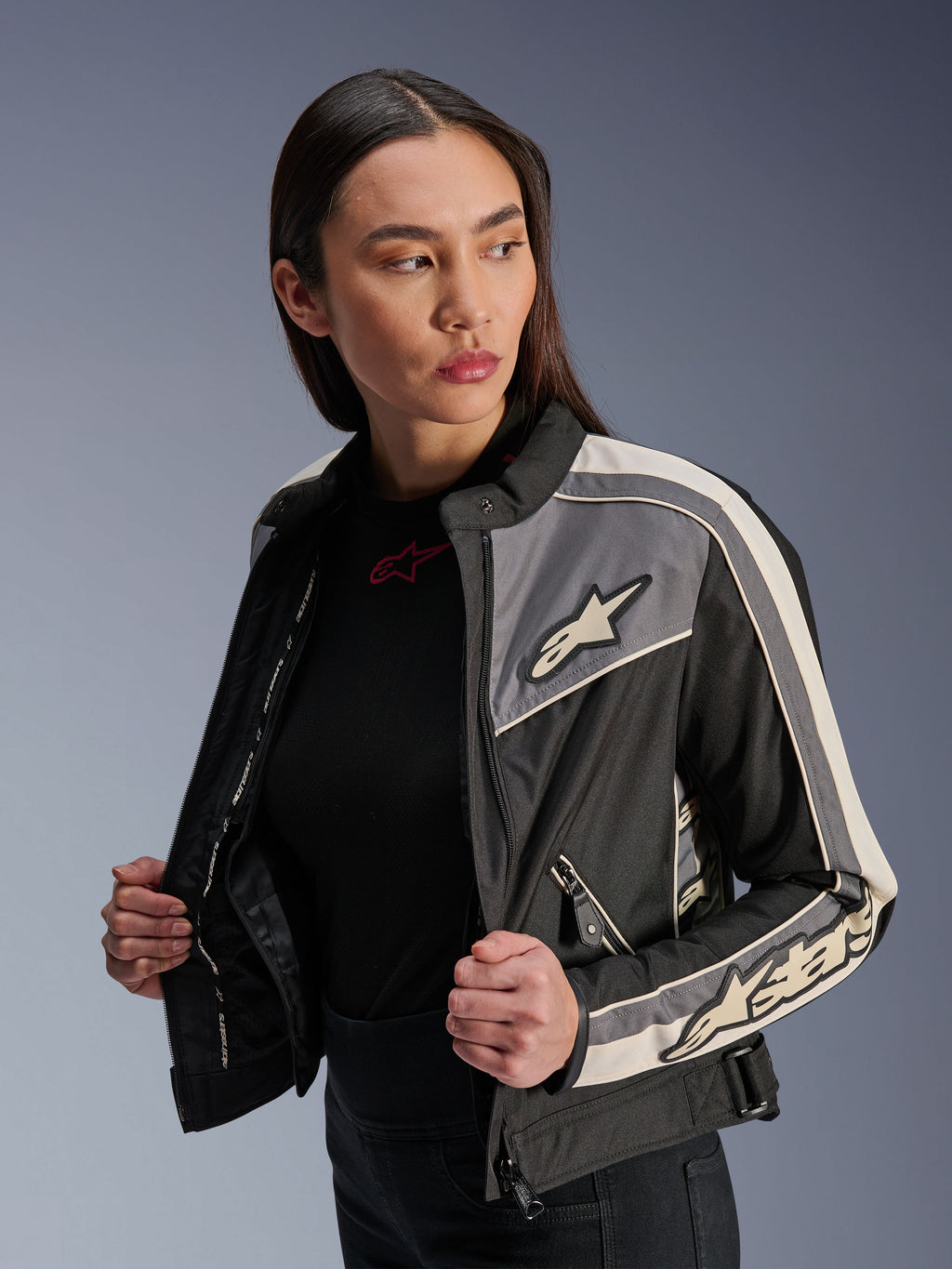Veste Alpinestars Stella T-Dyno WR pour femme, veste de moto en textile, noir, gris foncé et écru, design d'inspiration vintage avec des bandes sportives et des logos sur la poitrine et les manches, portée par un mannequin, équipement de route urbain