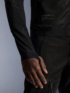 Veste Alpinestars Troop-Air, noire, gros plan montrant la construction en maille technique, écusson de la marque avec texte technique et manche avec passe-pouce intégré, veste de moto urbaine d'été à haute circulation d'air